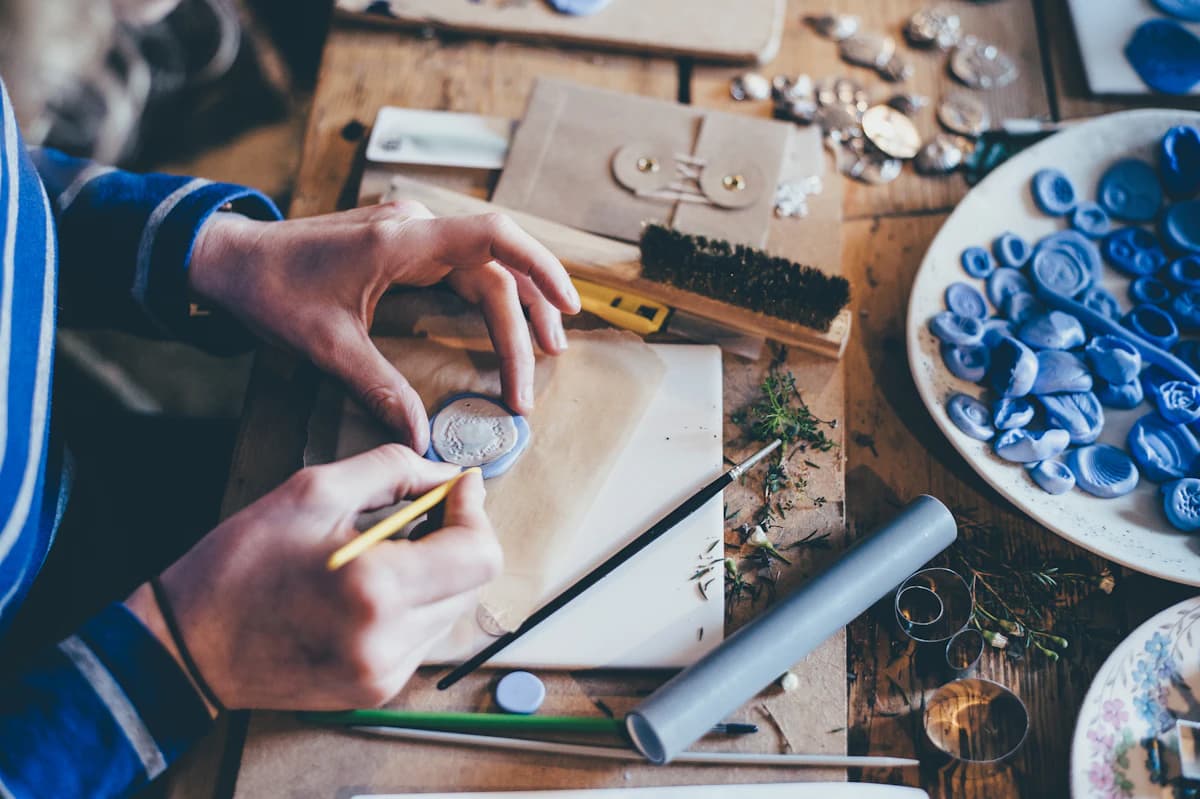 Creative seller testing Etsy product ideas with samples, notes, sketches, and a laptop